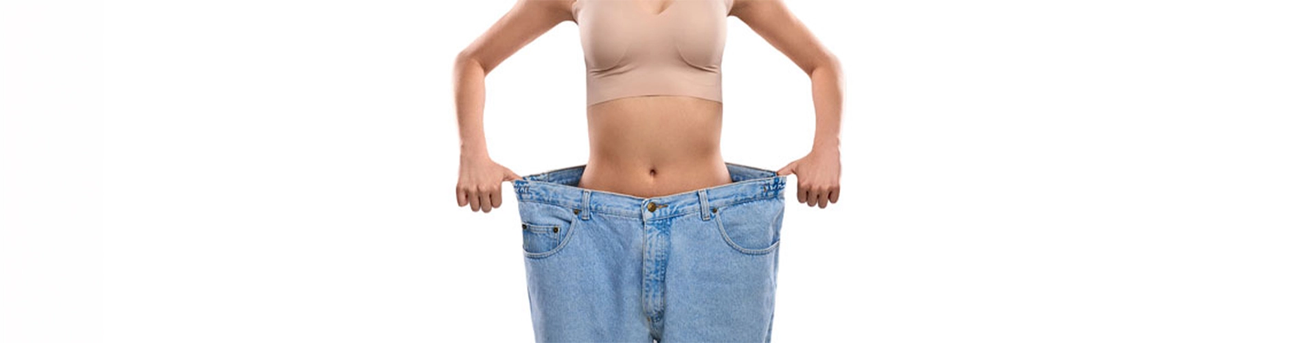 Hypnose-Abnehmen – sichtbarer Erfolg: schlanke Frau steht in viel zu großer Jeans nach Gewichtsverlust